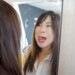 鏡越しに映る変顔の女性