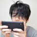 寝起きでスマホゲームをする男性